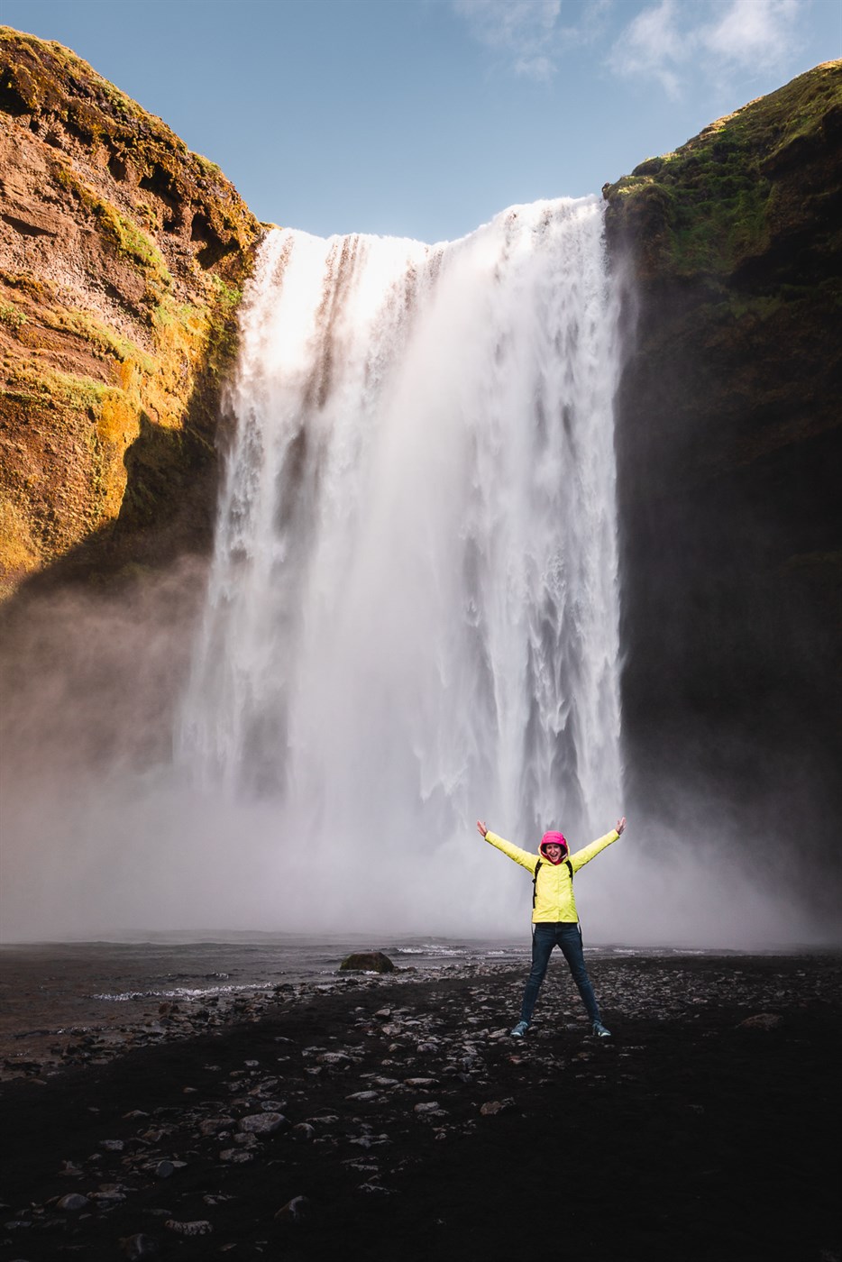Traveler striking a victory pose in front of Skógafoss, probably feeling like the main character (because they are).