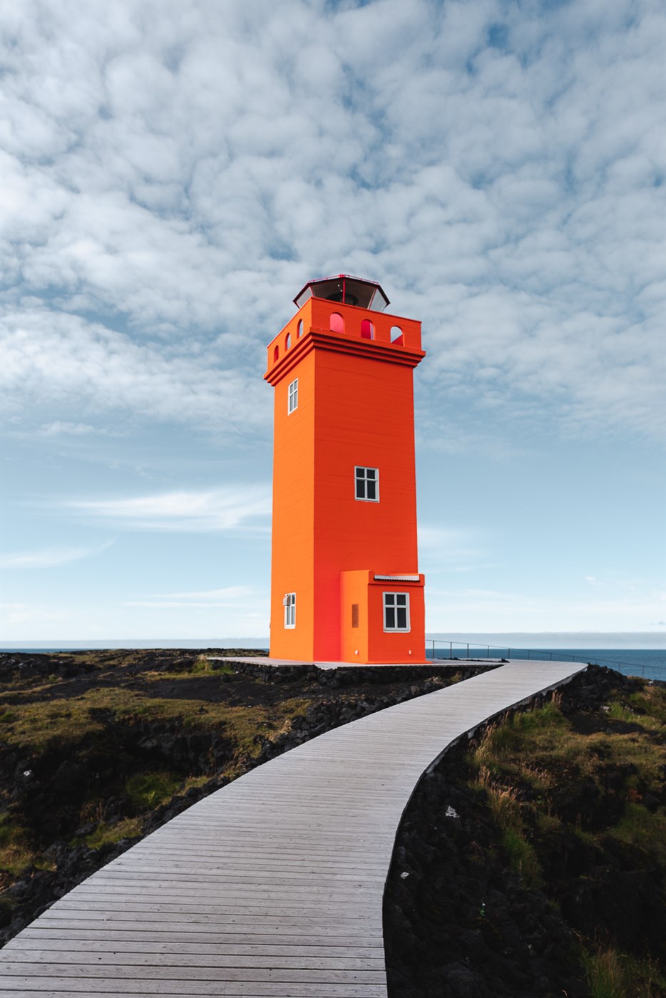 Bold, orange, and bizarrely charming – Svörtuloft Lighthouse stands tall by the sea, owning the lava cliffs like it pays rent.