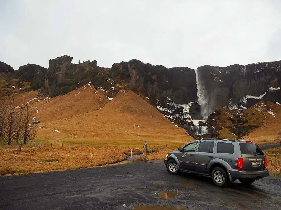 Car parked near a waterfall in Iceland, where quick stops quietly turn into long ones.