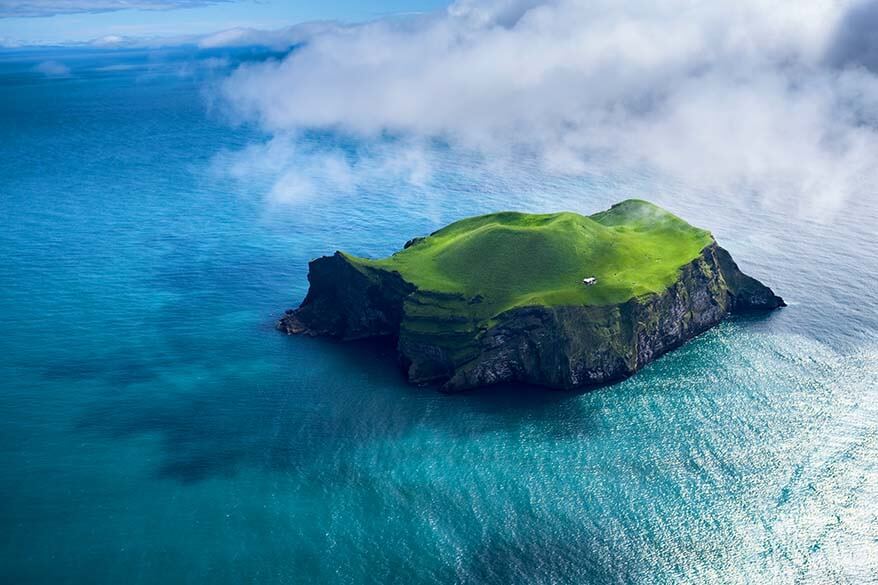 Remote green island in Iceland surrounded by ocean, looking like a rendering glitch.