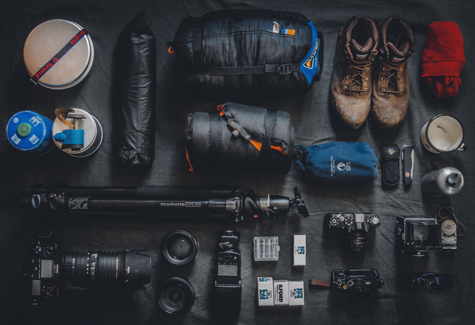 A full spread of camping and photography gear laid out before takeoff – from hiking boots to camera lenses, this is what serious Iceland packing looks like
