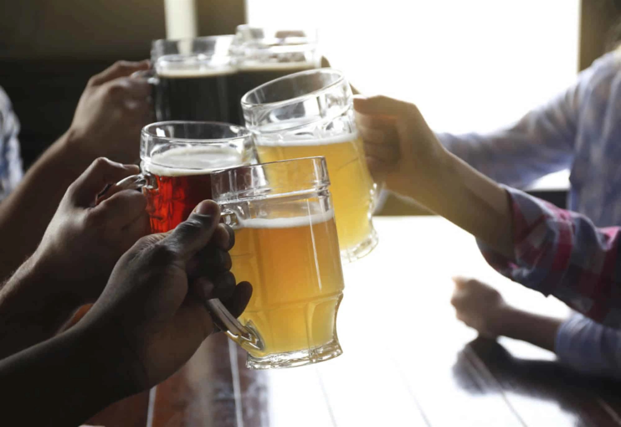 Friends toasting with mugs of beer in Iceland – because nothing says celebration like local brews and good company.