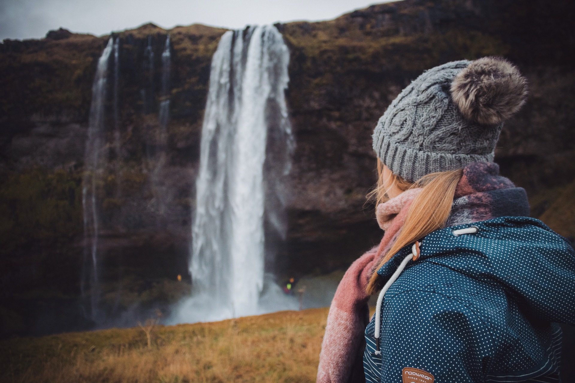 Woman looking at seljalandsfoss waterfall in Iceland