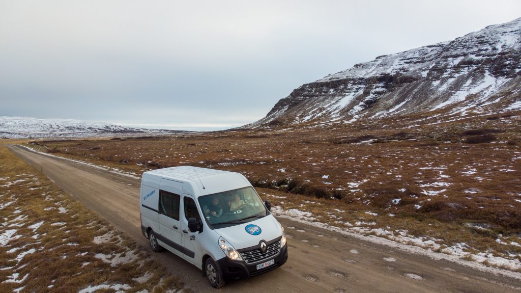 Campervan driving through cold Icelandic winter landscapes during a remote road trip in Iceland.