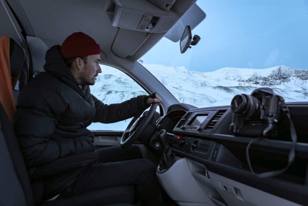 Traveler driving a campervan through snowy Iceland roads, highlighting winter road trip freedom and flexibility.