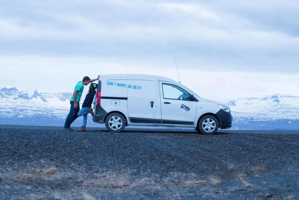 Travelers pushing a campervan through remote Iceland landscapes, showing the unpredictable reality of Iceland road trips and van travel.