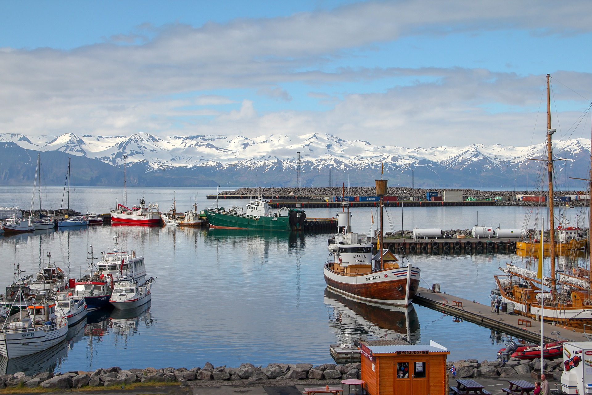 fishing harbor of Husavik with boats, docks, sea, mountains on the background