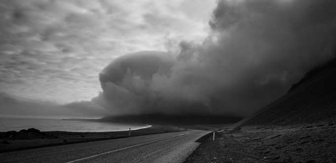 A massive sand and ash storm looms over the Icelandic coastline, a dramatic reminder of why sand and ash protection insurance in Iceland is worth it.