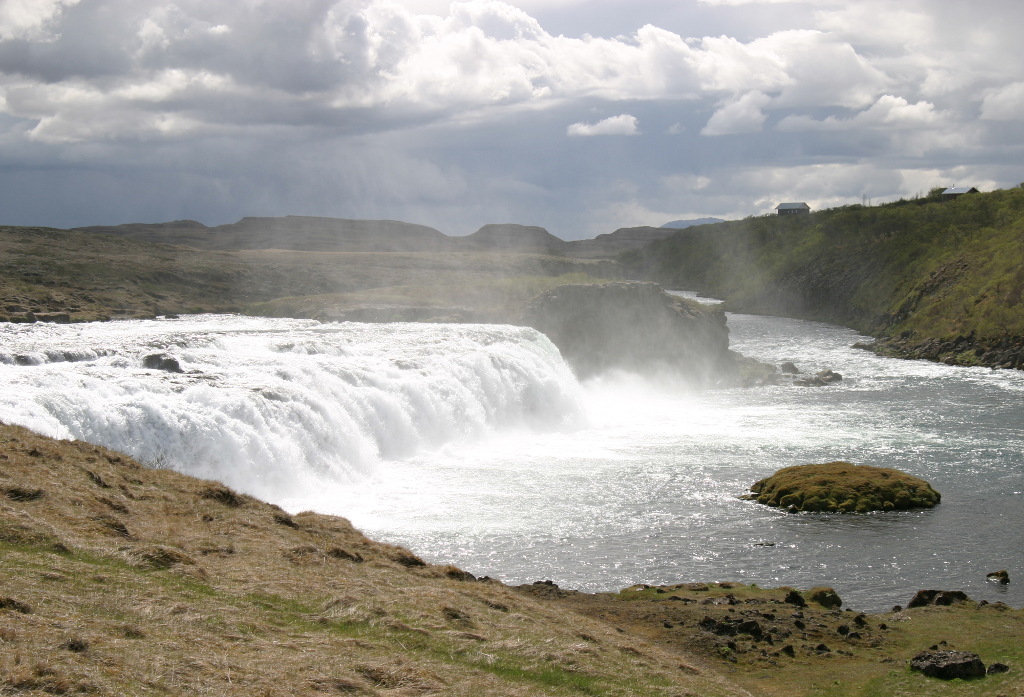 Power and Mist at Faxi Waterfall A dramatic shot of Faxi waterfall as it crashes into the river below, framed by rugged terrain and moody Icelandic skies.