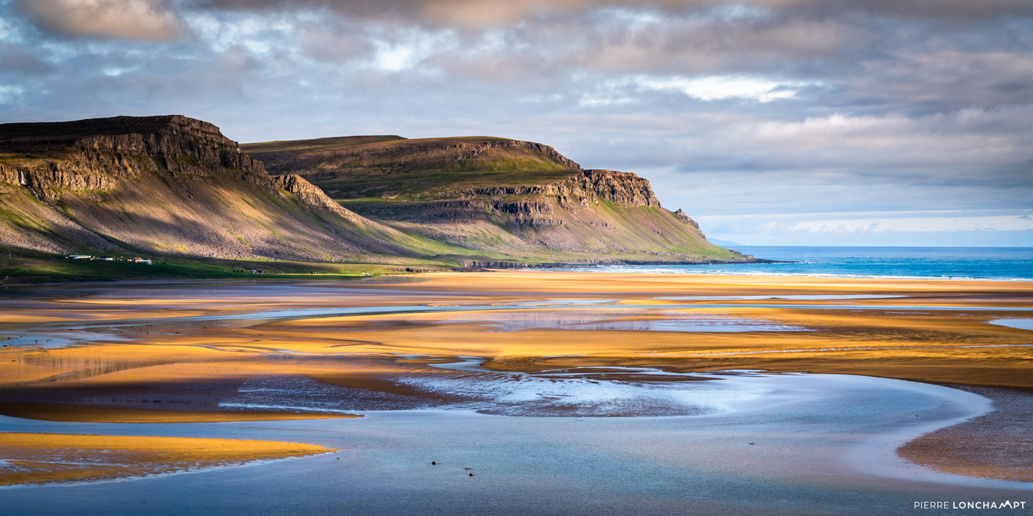 The vast golden sands of Rauðisandur beach with dramatic coastal cliffs, a peaceful retreat in Iceland’s Westfjords