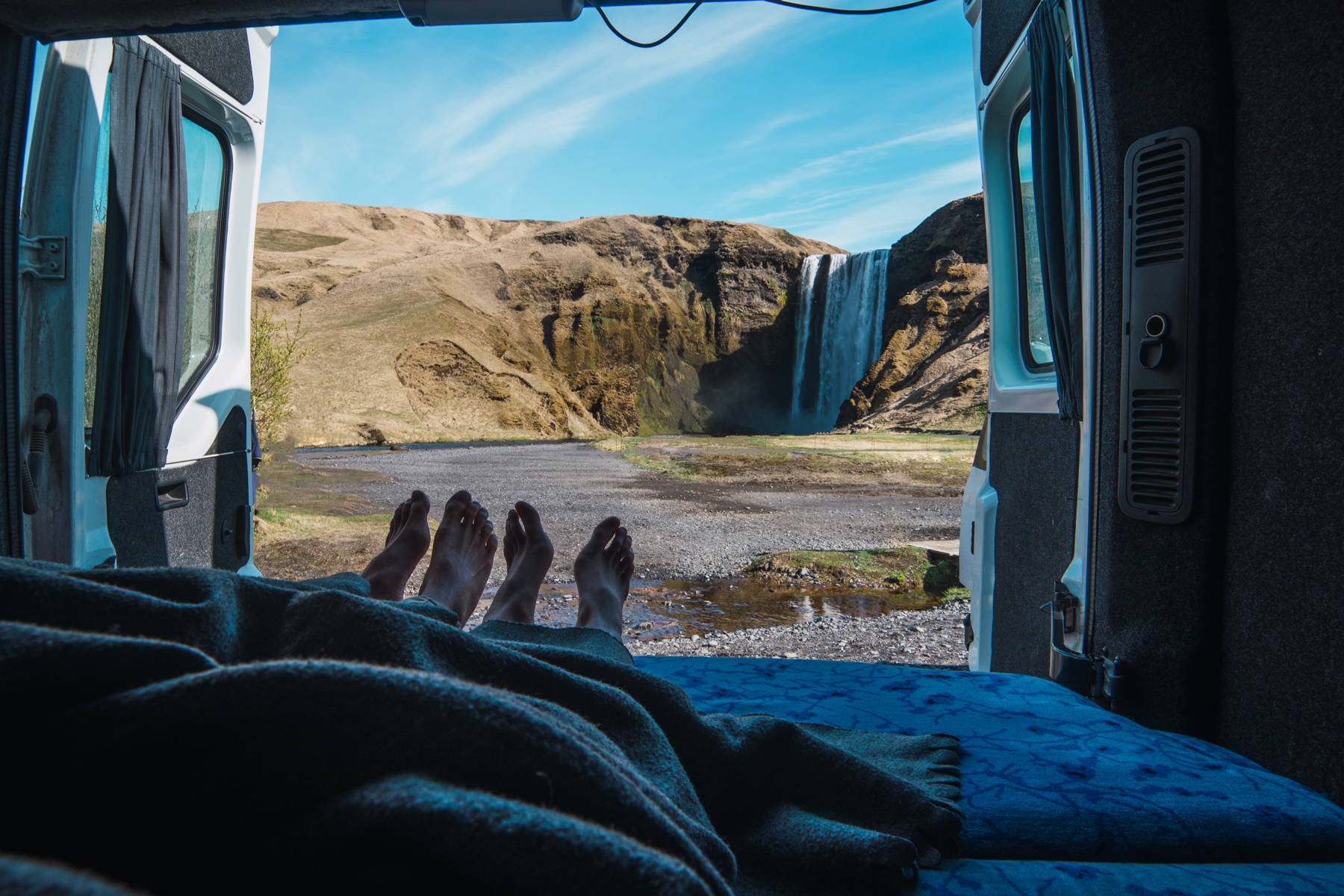 Relaxing In A Campervan In Iceland Cozy moment inside a campervan with a stunning view of Iceland’s rugged landscapes under the summer sun.
