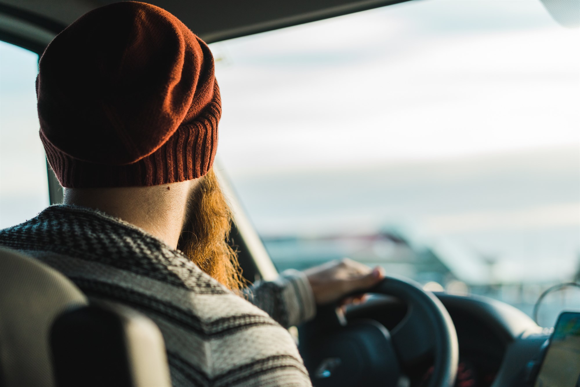 A bearded traveler behind the wheel of a campervan, soaking in the light and the open road ahead, ready for whatever Iceland decides to throw at him.