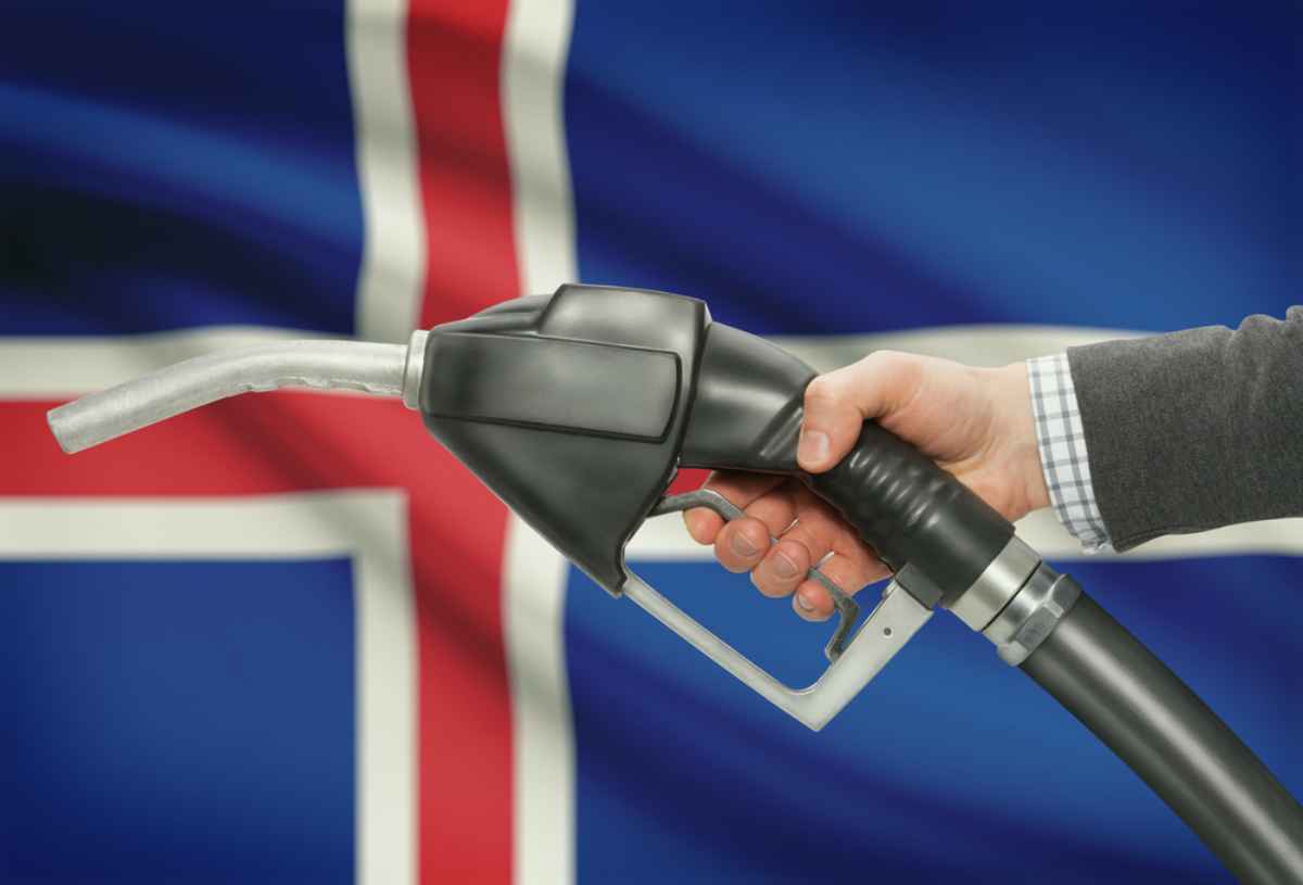 A fuel nozzle held against the Icelandic flag, a reminder that long stretches of empty road deserve respect, planning and a full tank.