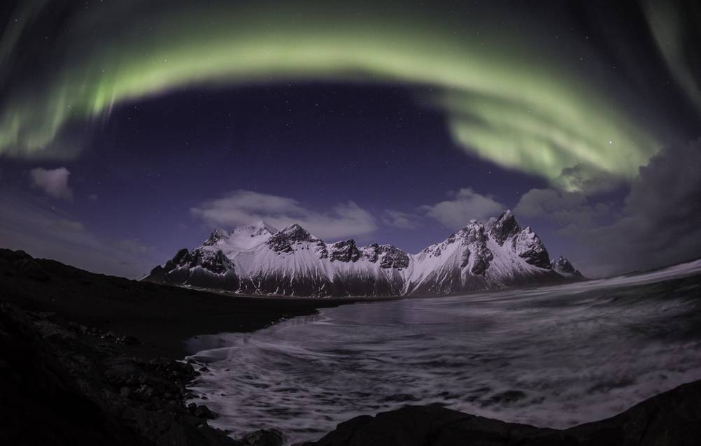 Stokksnes Black Sand Beach with green northern lights in the sky and Vestrahorn in the background 