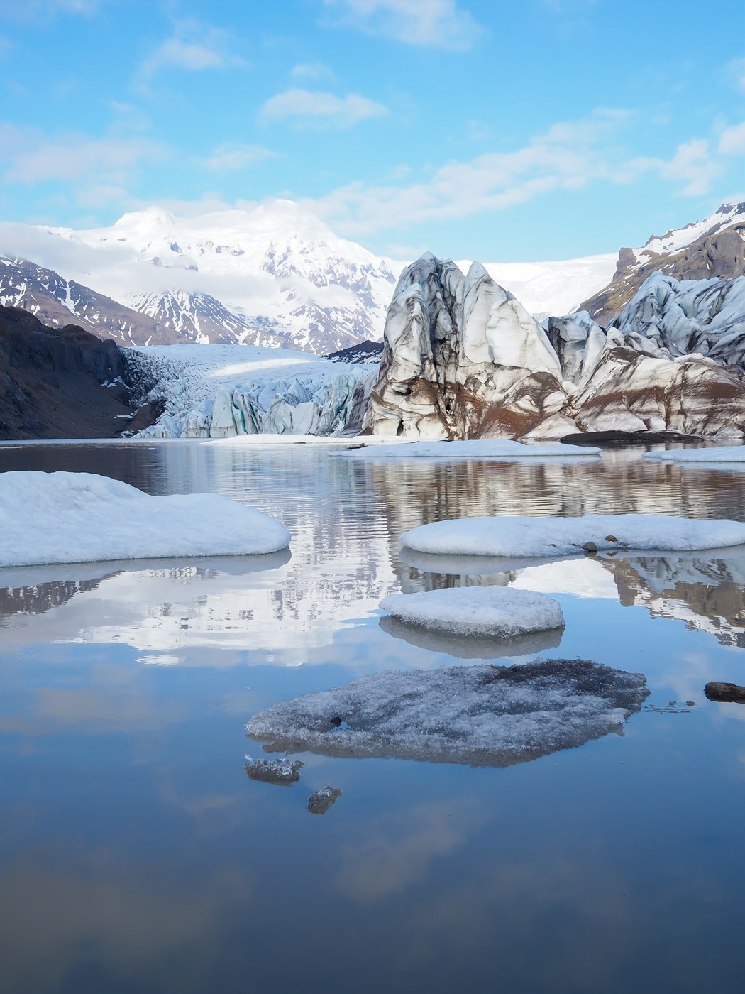 A stunning view of Svínafellsjökull, a majestic outlet glacier of Vatnajökull, with floating ice chunks mirrored in the water