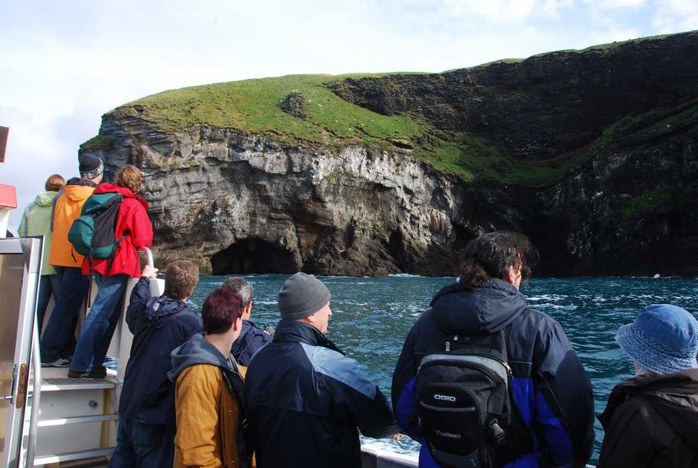 People on a boat looking at a cliff in Iceland, body of water