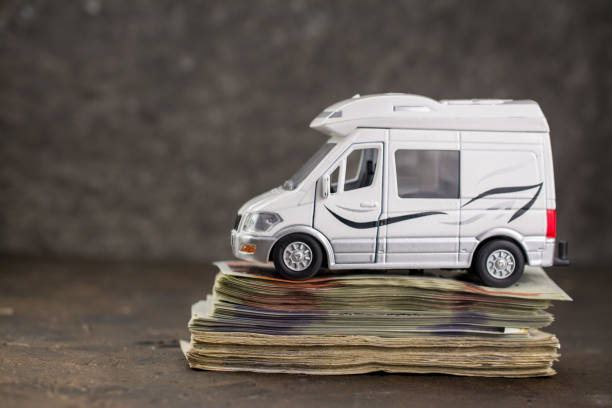 How Much Is the Deposit for a Campervan in Iceland? Toy van on a stack of bills illustrating security deposit requirements for Iceland camper rental.