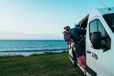 Friends enjoying campervan life by the Icelandic coast during a summer road trip around the island.