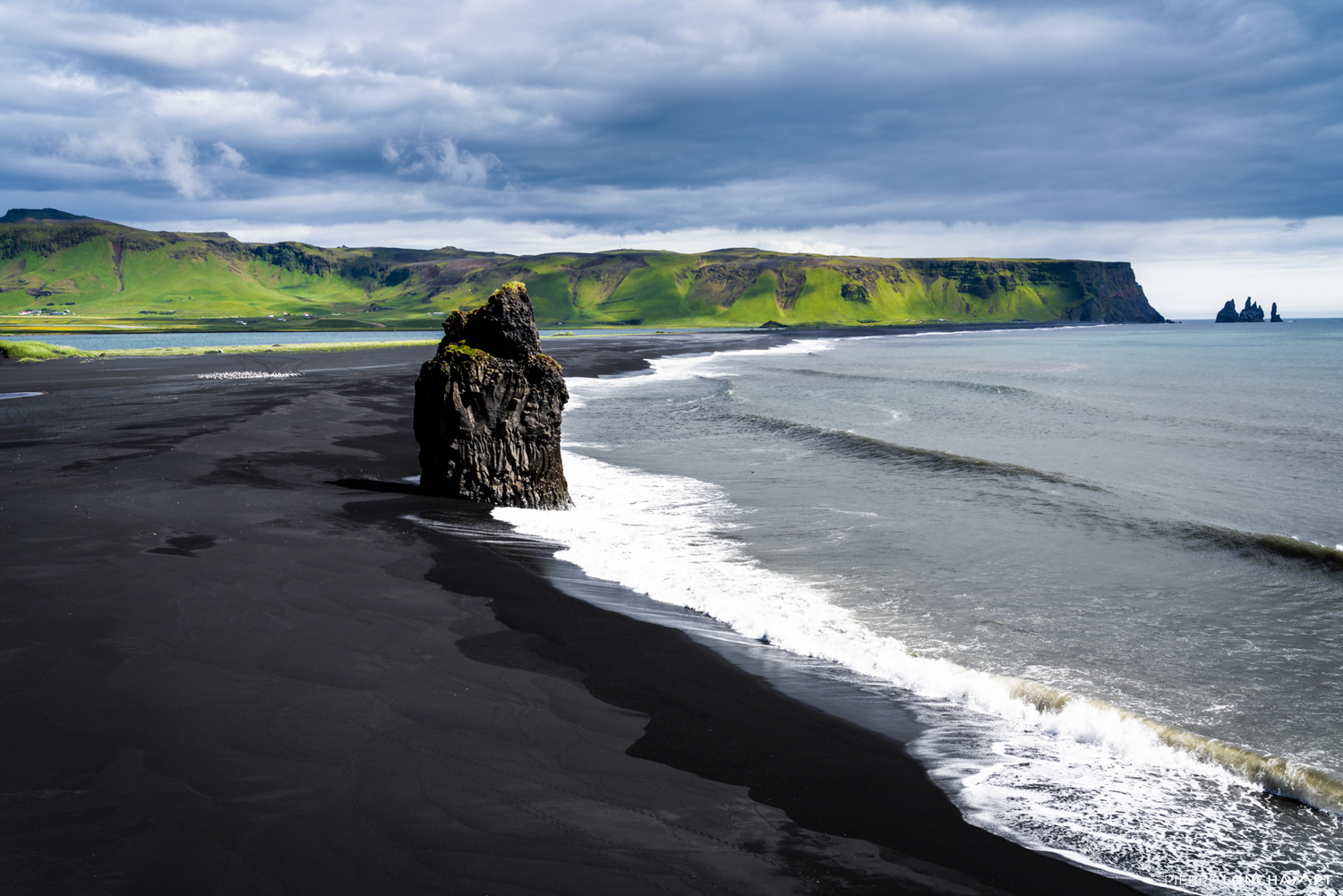 The iconic black sand beach of Reynisfjara, featuring towering sea stacks and volcanic cliffs, a must-visit on any Iceland road trip