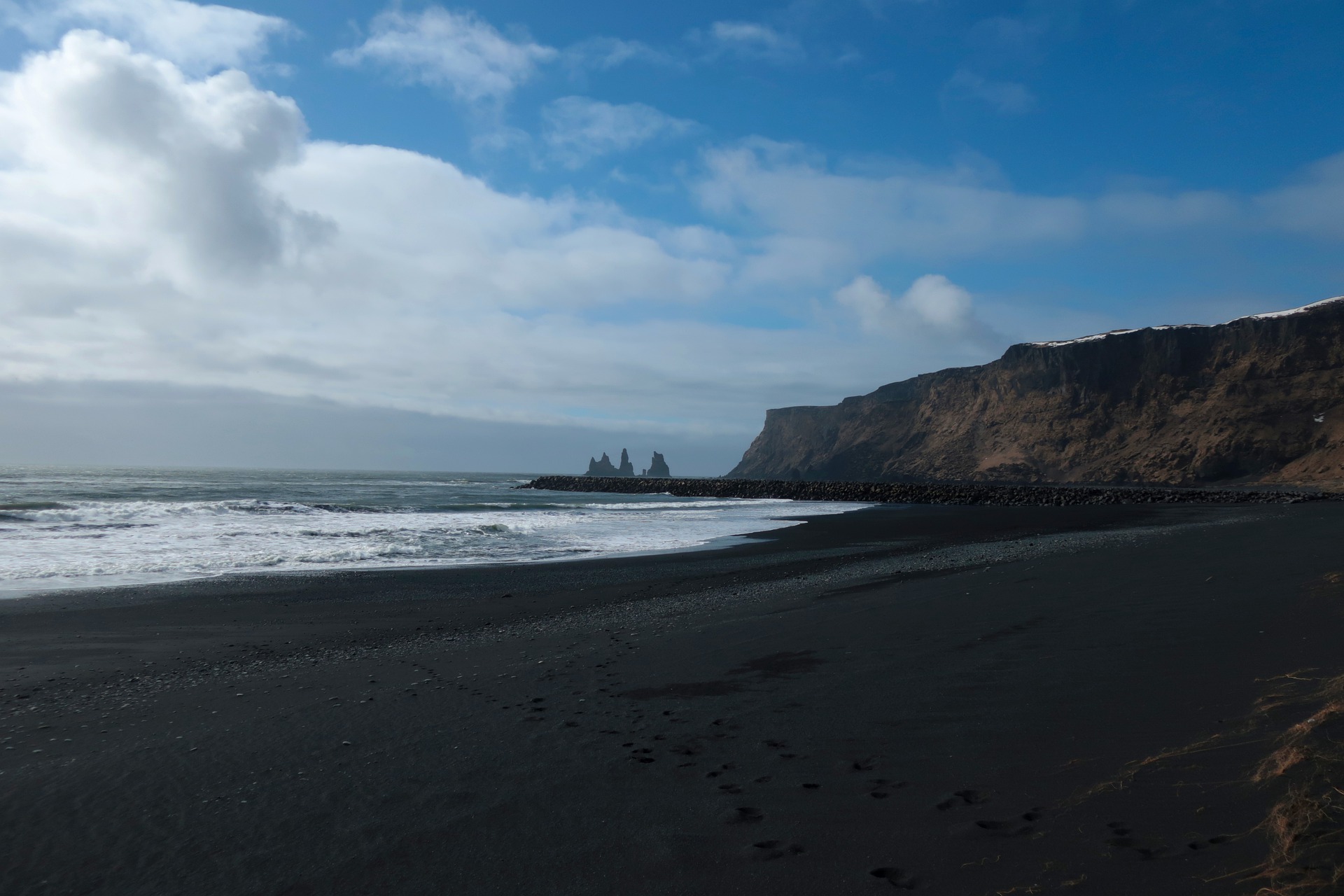 black sand beach in vik in iceland, cliffs, sea, waves, blue sky