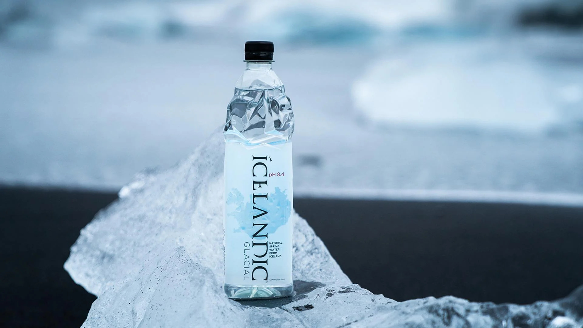 Bottled water placed on glacier ice in Iceland, highlighting the contrast between commercial water and natural purity.