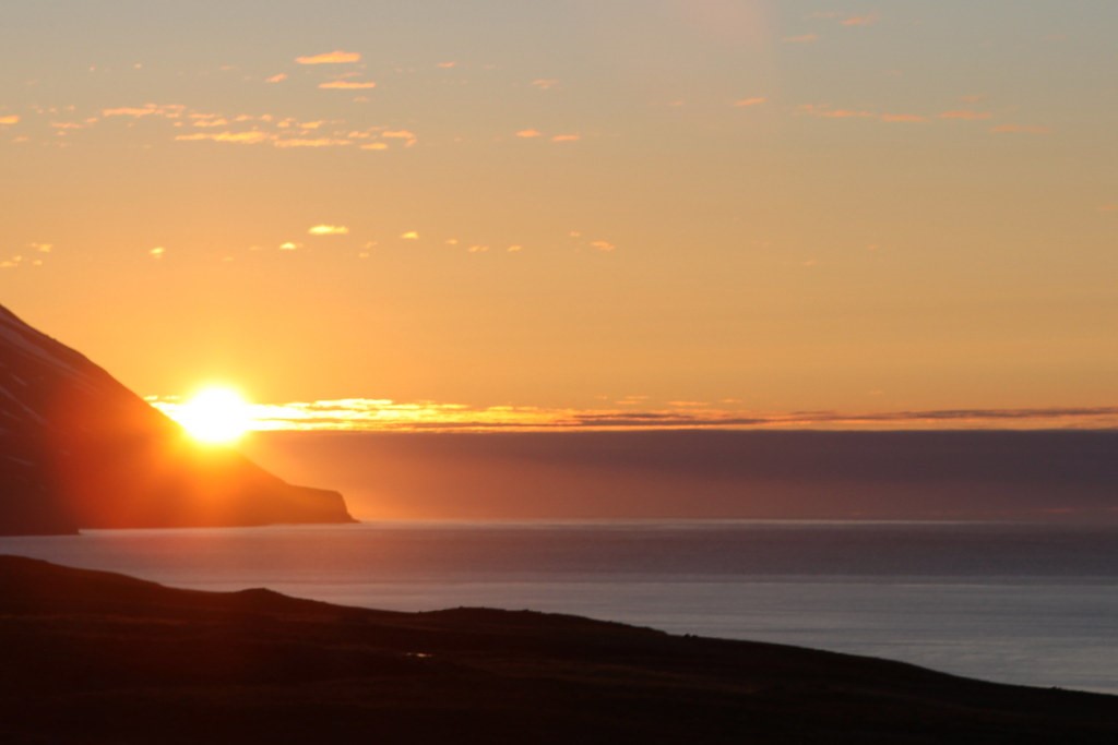 midnight sun in Dalvik iceland over the sea and mountains